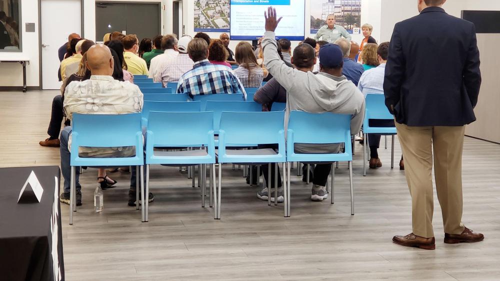 Community engagement meeting with a hand raised