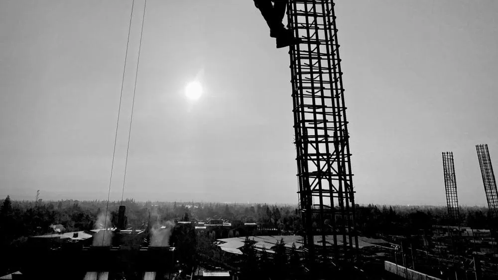An April 2023 contest winner features a black and white image of a construction working backlit by the sun, climbing a column of a future Aggie Square building. Photo by Louie Jordan.