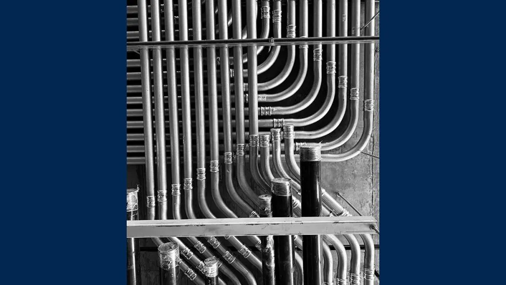 The first-place August 2023 photo contest winner features a black and white snapshot of piping and conduit installed on a ceiling. Photo by Thomas O'Brien.