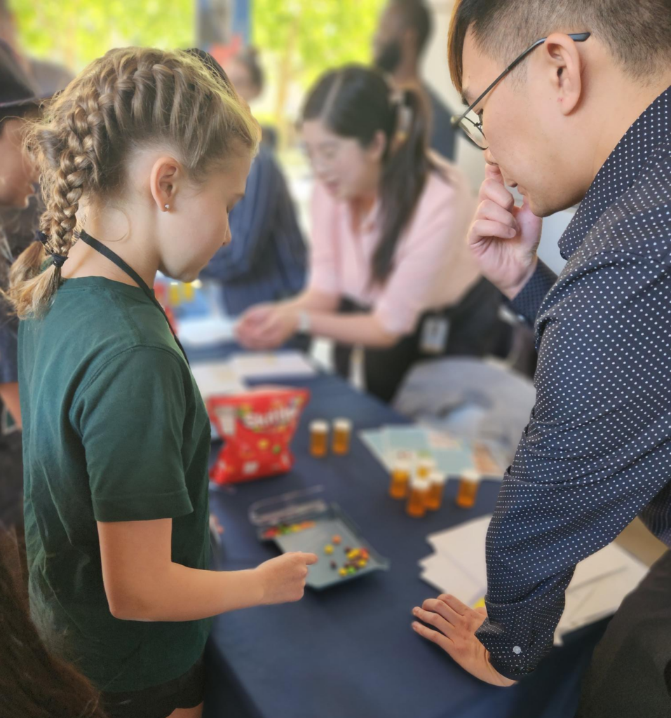 One of the students carefully counts pieces of candy, an activity to simulate filling prescriptions, as a one of the instructors observes.