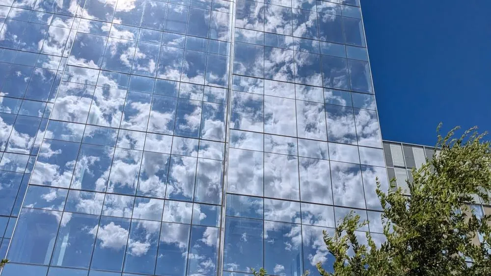 The first-place winner for July 2024 pictures the beautiful visuals of the clouds' reflection on the glasswork of the Aggie Square buildings. Photo by Audrey Garvey.
