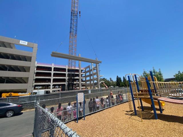 Students watch the crane place a large concrete piece onto the sixth floor of the parking structure.