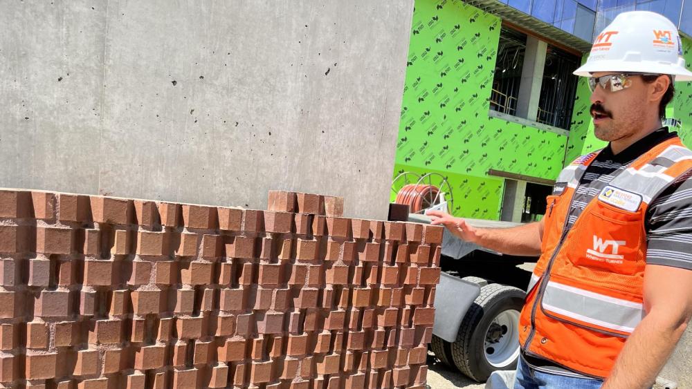 Tommy DeArmond, Assistant Project Manager with Whiting-Turner, the Aggie Square general contractor shows a test installation of the bricks to evaluate different grout colors and textures.